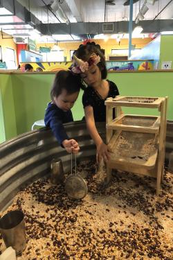 Children playing in the metal tub filled with seeds
